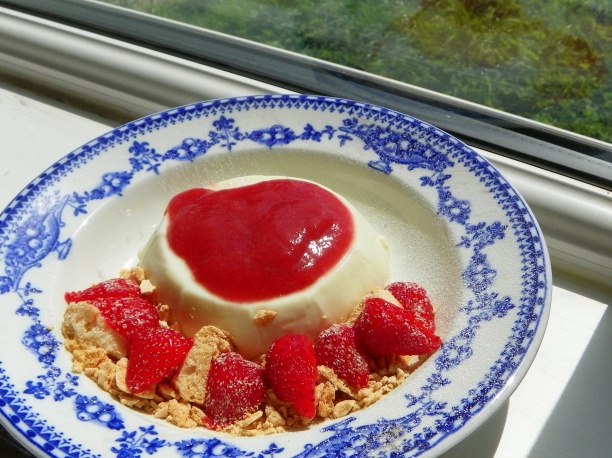 Vanilla panna cotta with crushed meringue, strawberries and rhubarb coulis